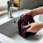 Mains lavant un tissu bordeaux sous l'eau courante