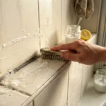 Main brossant un rebord de fenêtre avec produit naturel